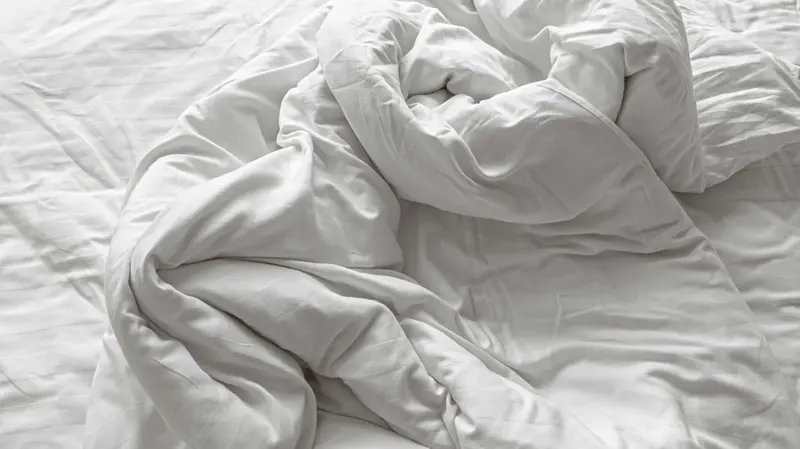 Couette blanche au froissé généreux dans une lumière naturelle douce