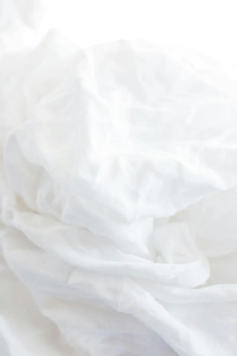 Gros plan sur la texture d'un drap blanc posé sur le lit