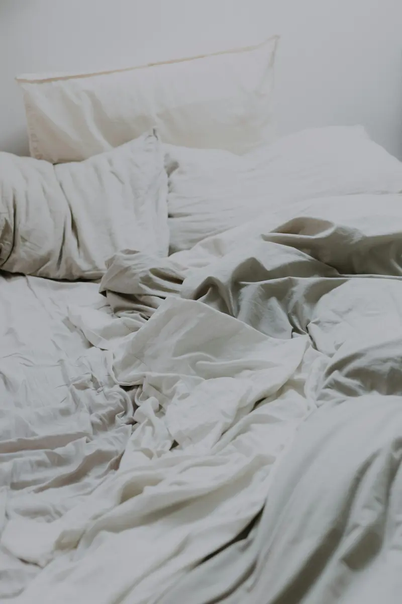 Couette et oreillers blancs au froissé naturel dans une lumière douce