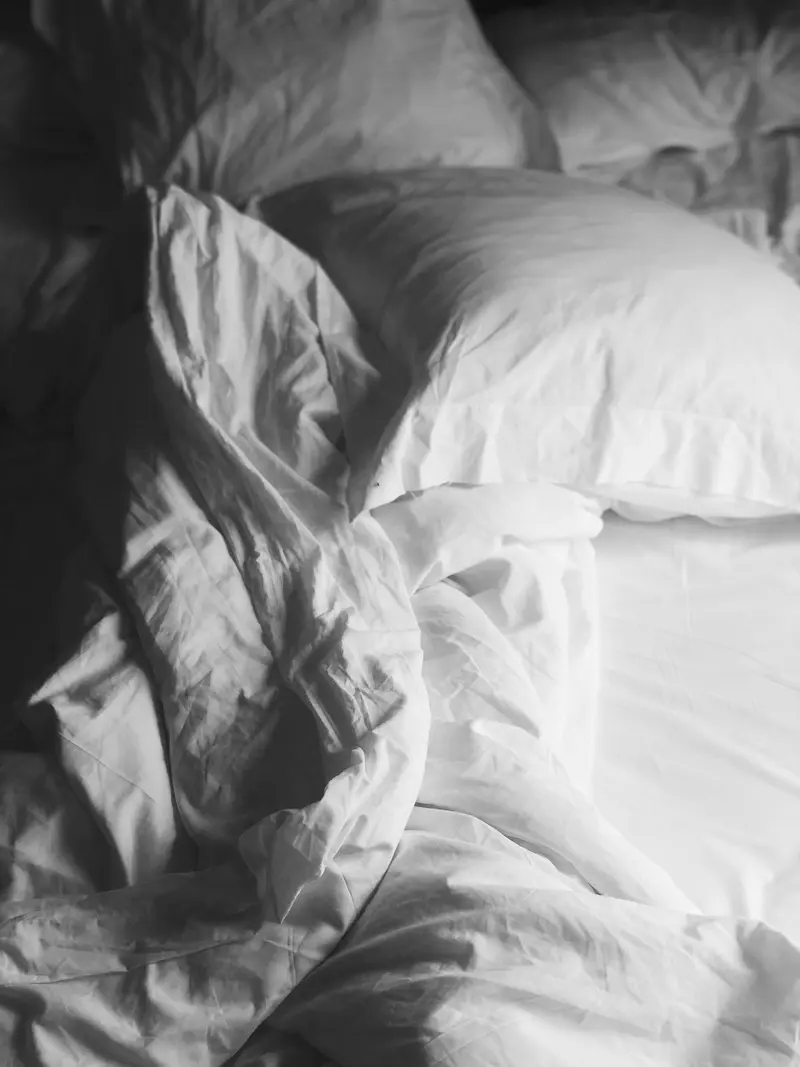 Parure de lit blanche avec oreillers moelleux, lumière naturelle douce