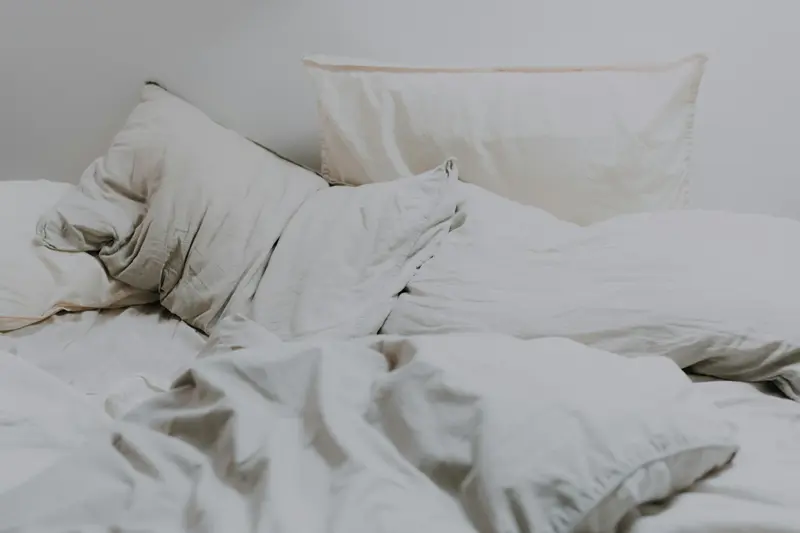 Taies d'oreiller blanches en coton sur un lit à la lumière tamisée